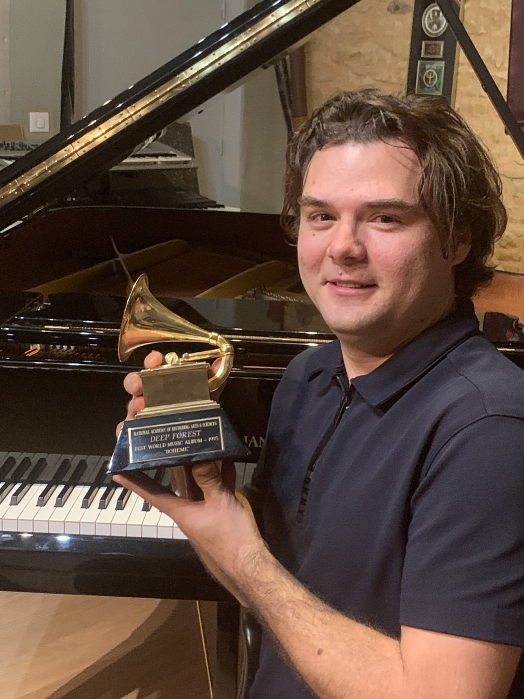 Ilya Truskovsky at the piano holding Deep Forest's Grammy Award